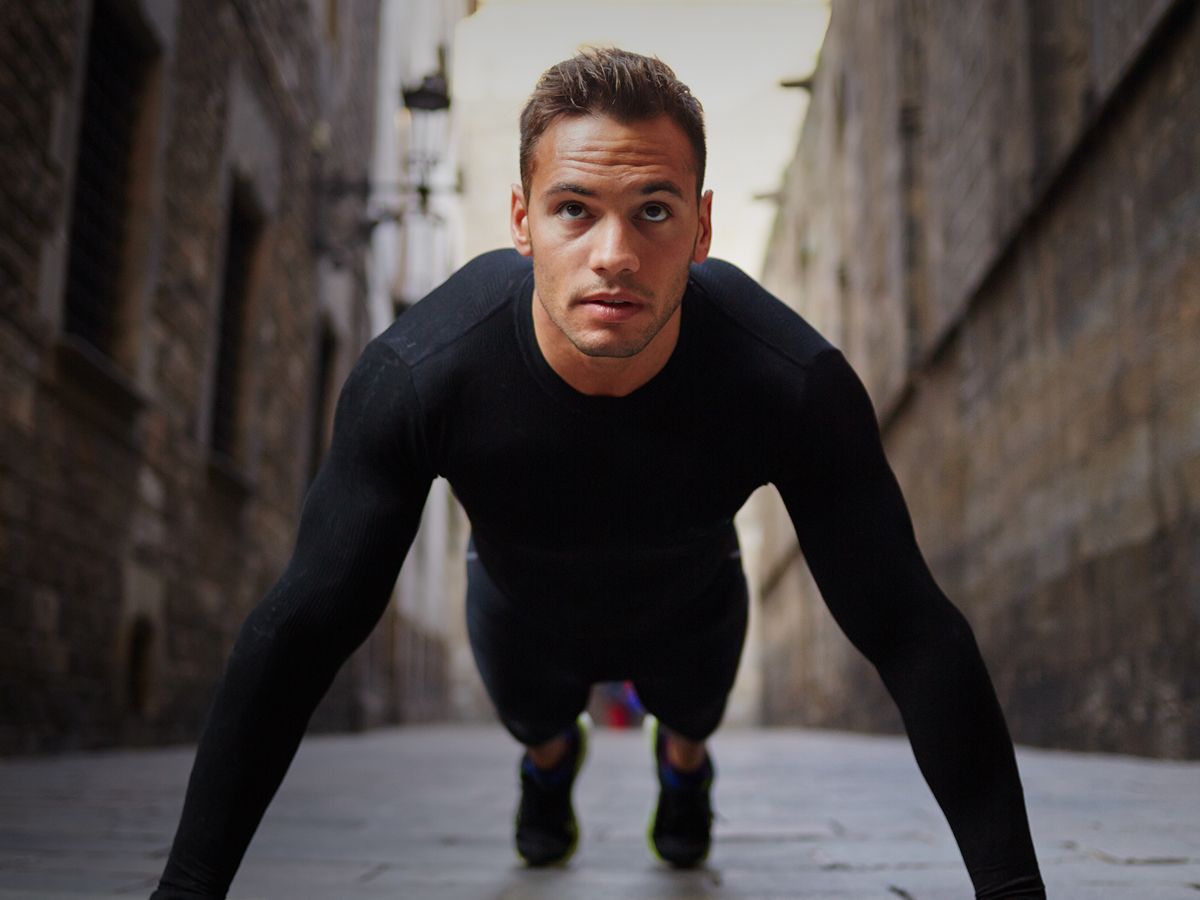 Dallas HBOT model doing push-ups in urban alleyway.